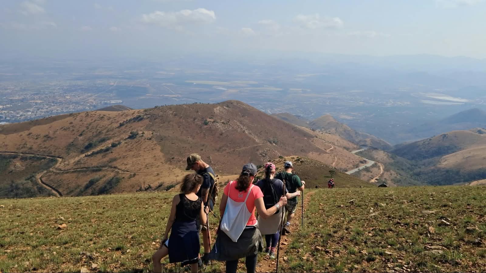 Hikers on a high ridge with sweeping views over the lowveld at dusk